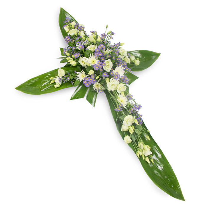 A gentle, reverent composition captured from a slightly raised angle, this cross-shaped floral piece rests on an immaculate white background so every element reads clearly: large tropical green leaves-probably Ti leaves-create a structured, verdant base with visible veins and a subtle lustre that anchors the design. Concentrated at the cross's centre and extending along the arms are abundant clusters of soft white and creamy lisianthus, their ruffled petals unfolding with a fragile elegance that suggests purity and solace. Interspersed among them are compact white chrysanthemum-type blooms that add a clean, luminous texture, while sprays of tiny lavender or pale purple flowers-most likely limonium or small asters-provide a tender, cool counterpoint that deepens the palette without overwhelming it. Fine green fillers thread through the bouquets, bridging the smooth leaf planes and the feathery flower clusters. The lighting is even and calm, accentuating the petal curves and the waxy sheen of the foliage, and inviting quiet reflection. This arrangement carries a spiritual tone suited to funerals, memorial services, or church altars and is often selected by local families who want a classic, faith-oriented expression of remembrance. It speaks of continuity-of evergreen strength beneath ephemeral blooms-and would be appropriate for services at parish churches or civic venues serving Hook, Odiham and nearby Basingstoke communities, offering a respectful, enduring gesture of condolence.