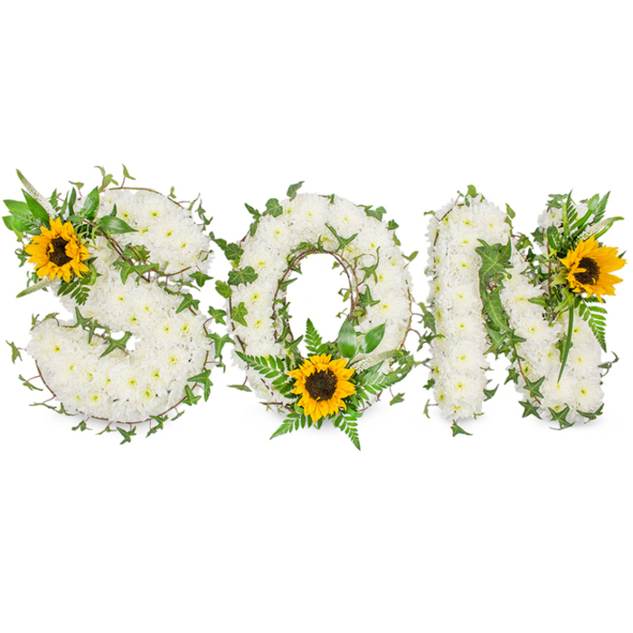 A meticulously hand-crafted memorial piece spells out SON in capital letters, each letter robustly formed from a dense layer of immaculate white chrysanthemums that create a soft, pillowy texture across the entire display. Interwoven through the white floral base are winding tendrils of dark green ivy and assorted leafy sprigs, including lighter green fern fronds whose feathery shapes sit against pointed leaves to add contrast and three-dimensional definition. Three vibrant sunflowers provide focal points: one is set into the upper-left curve of the S, another nestles in the lower arc of the O among a cluster of fern foliage, and the third decorates the upper-right of the N - every sunflower showing broad golden petals radiating from a textured dark brown centre. The piece is photographed on a stark white backdrop with soft, directional studio lighting that accentuates the chrysanthemums' velvety texture and the foliage's glossy greens while keeping the sunflowers' warmth true to life. From a florist's perspective in Hook, I imagine this tribute arriving at a funeral directors' chapel off the A30 or being placed at a service near Hook railway station, offering clear lettering and comforting symbolism for mourners who are travelling from nearby Basingstoke or North Warnborough. The overall impression is reverent and tender, using classic sympathy whites and foliage with the hopeful brightness of sunflowers to convey love, respect and the enduring memory of a son.