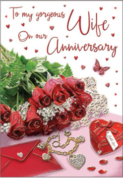 This anniversary card composition looks like a cherished memory captured in still life, the sort of detail a thoughtful couple in Hook might display on a bedside table. The focus is a cluster of classic red roses, their petals lush, spiralled, and intensely saturated, almost glowing with colour against the neutral background. The blooms nestle into fresh greenery, the leaves adding texture and contrast that makes the red even more dramatic. Set close by is an elegant envelope positioned at a gentle angle, hinting at a heartfelt message written within, perhaps recalling evenings spent walking through Hook's village centre. A dainty jewellery piece, possibly a bracelet or fine necklace, is laid out with care, its metallic sheen catching the soft daylight and adding a hint of luxury. Nearby stands a small, heart-shaped keepsake box in deep red, its smooth surface reflecting tiny highlights. Scattered around are miniature hearts and glimmering embellishments, like sparkling table confetti used for a special anniversary dinner. A single butterfly detail brings lightness, as though symbolising transformation and the way love deepens over time. The text of the card is visible in places, written in a graceful script that arcs around the roses and decorations without overwhelming them. Gentle shadows give depth to the entire arrangement, while the warm, balanced lighting wraps every object in a sense of calm and affection. The scene feels quietly celebratory and deeply intimate, a visual love letter composed with the care of an experienced florist and the tenderness of two people marking another year together.