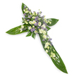 Set against a clean white backdrop and photographed from a slight overhead angle, this dignified floral cross is crafted from broad, glossy tropical leaves-likely Ti leaves-whose deep green surfaces and visible veins form the structural arms and central point of the Christian cross. At the intersection and running along each arm, dense clusters of soft, ruffled lisianthus in creamy ivory and pure white create a plush, calming focal mass, interspersed with small daisy-like white chrysanthemums that pick up light and add gentle brightness. Scattered through the clusters are sprays of tiny, star-shaped lavender or pale purple fillers-limonium or asters-that introduce a quiet cool contrast and a sense of depth. Finer green filler foliage threads through the blooms, softening edges and lending a subtle, natural texture against the waxy leaves. The light is even and soft, bathing the arrangement in a serene radiance that emphasises the delicate petal edges and the sheen of the leaves without harsh shadows. The scent, if imagined, is faintly green and floral rather than sweet-an understated fragrance suitable for reflective moments. This composition reads as a traditional sympathy tribute: peaceful, restrained and respectful, meant for wakes, funeral services, or graveside remembrances. Florally, it balances the permanence of the verdant leaf base with the transient grace of the blooms to convey consolation and hope. Locally, this style is often chosen by families around Hook and nearby villages seeking a classic, faith-centered expression of condolence for services at parish churches or community memorials.